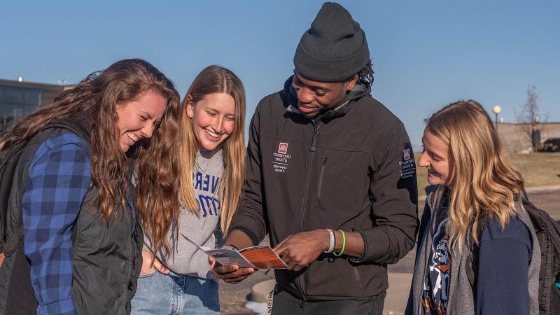 Campus Safety & Security employee showing three female students a campus map.